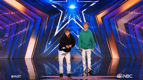 two young men are standing on a stage in front of a star .