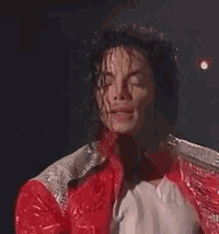 a close up of a man wearing a red jacket and a white shirt