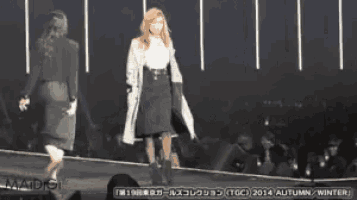 two women are walking down a runway with the year 2014 on the bottom left