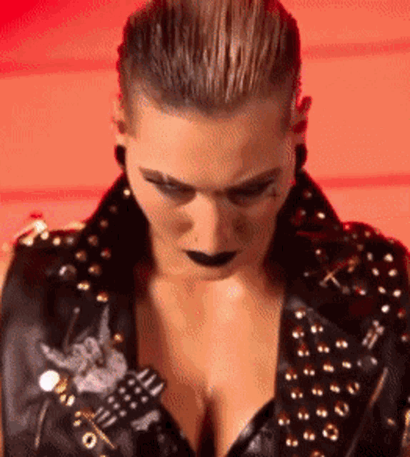 a close up of a woman wearing a black vest with studs
