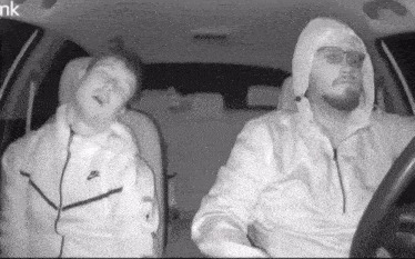 a man in a white nike jacket is driving a car