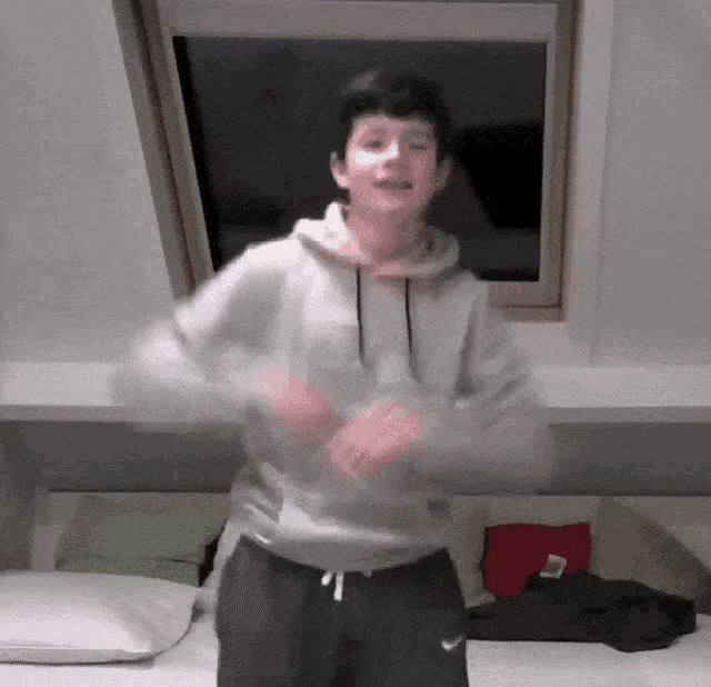 a boy in a grey hoodie and black nike shorts is dancing