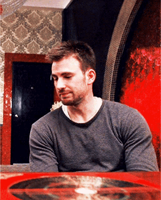 a man wearing a grey sweater sits at a table