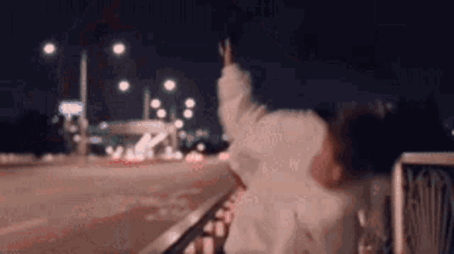 a blurry picture of a person standing on a railing at night .
