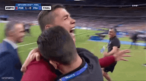 a man wearing a france lanyard hugs another man on a soccer field