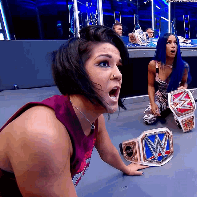 a female wrestler is kneeling down with a wwe championship belt next to her