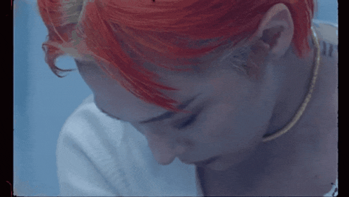 a close up of a person 's face with red hair and a gold necklace