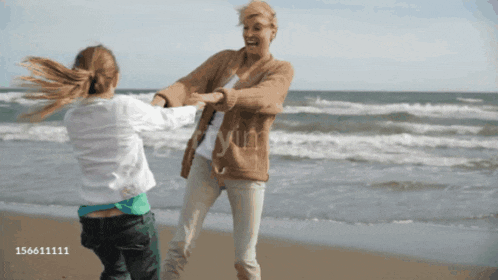 a woman and a girl are dancing on the beach with the number 156611111 in the lower right corner