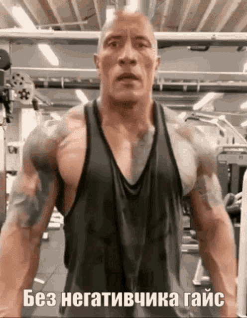 a muscular man in a tank top is standing in a gym with a foreign language .