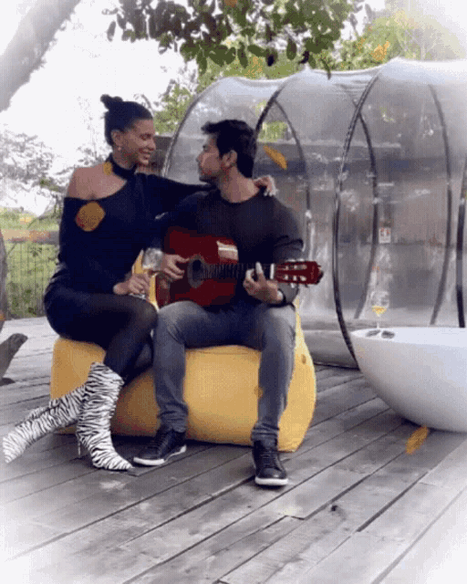 a man playing a guitar next to a woman