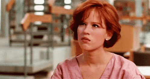 a woman with red hair is wearing a pink shirt and earrings .