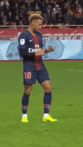 a soccer player wearing a fly emirates jersey is dancing on the field