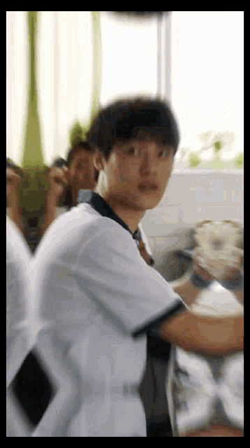 a man in a white shirt is standing in front of a group of people .