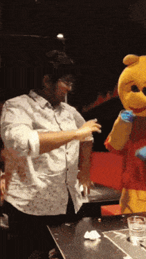 a man in a winnie the pooh costume stands next to a man in a white shirt