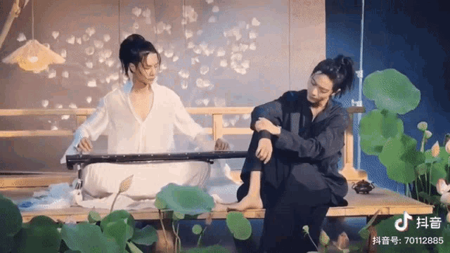 a man is playing a musical instrument while a woman sits next to him .