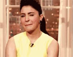 a woman in a yellow shirt is sitting in front of a window with her eyes closed .