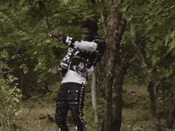 a man wearing a jacket that says secret stands in the woods