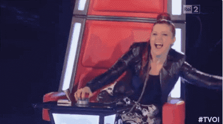 a woman is laughing while sitting in a chair on a television show .