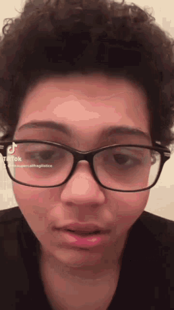 a close up of a person wearing glasses with a tiktok sticker