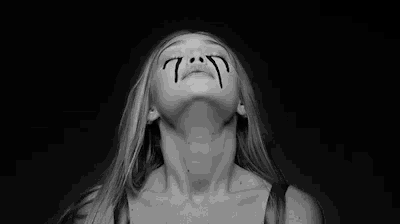 a woman is crying in a black and white photo with tears running down her face .
