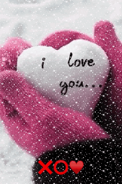 a person wearing pink mittens holds a heart that says i love you