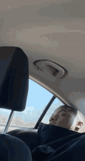 a person is sleeping in a car with their eyes closed .