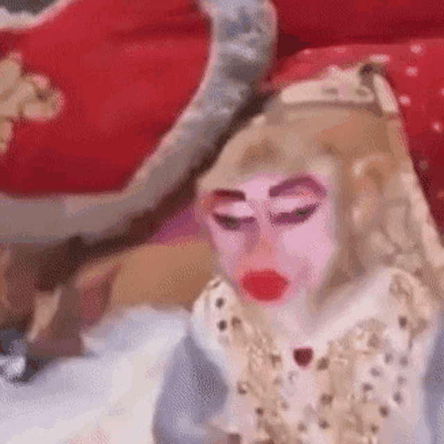 a monkey with a pink face and red lips is sitting on a bed .