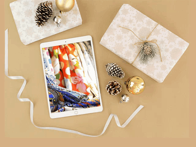 a tablet is surrounded by christmas decorations and wrapped presents