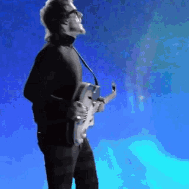 a man is playing a guitar in front of a blue sky