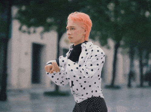 a woman with pink hair wearing a polka dot shirt