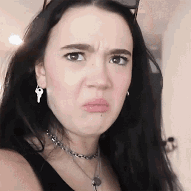 a woman wearing a choker and earrings with keys on them makes a funny face
