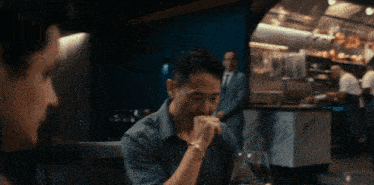 a man sitting at a table in a restaurant with a glass of wine