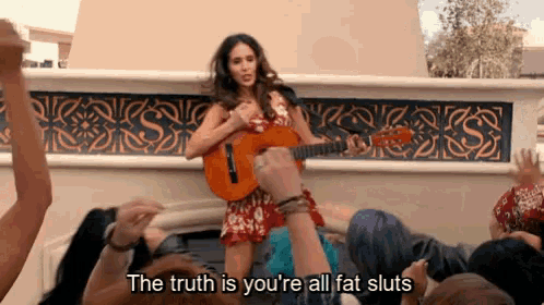 a woman playing a guitar in front of a crowd with the words " the truth is you 're all fat sluts " below her
