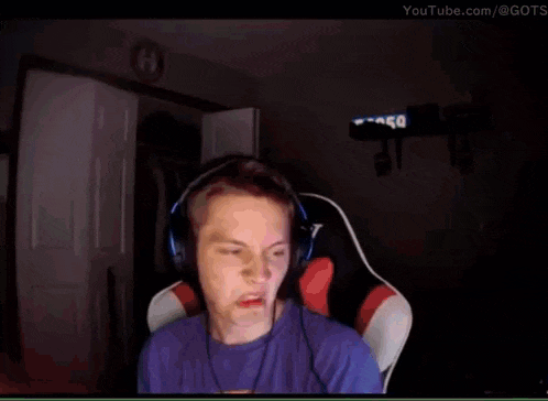 a young man wearing headphones and a blue shirt is making a funny face .