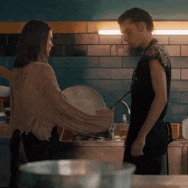 a man and a woman are standing in front of a sink