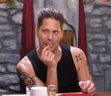 a man with a tattoo on his arm is sitting at a table eating
