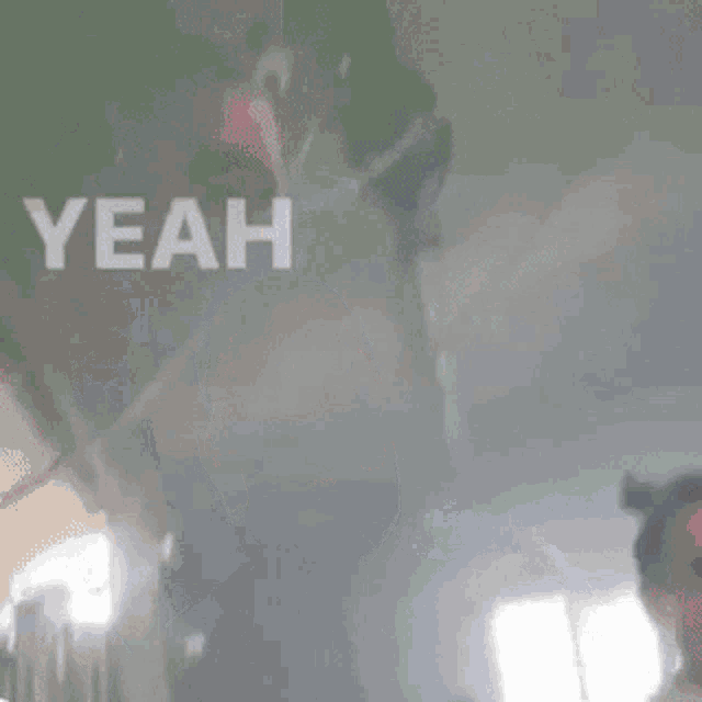 a man with a beard is standing in a dark room with the word yeah written above him