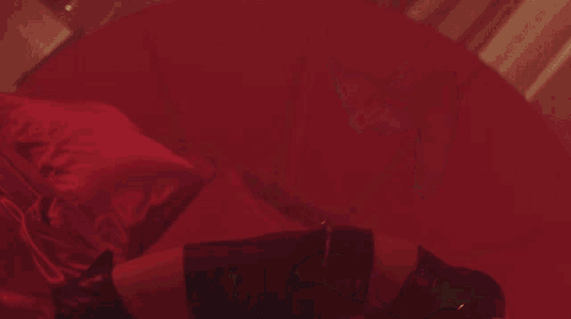 a woman is laying on a red couch in a dark room