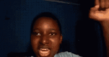 a close up of a person 's face with their mouth open and their hand in the air .