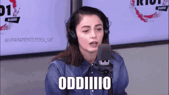 a woman wearing headphones is standing in front of a microphone and saying oddiiiiio .