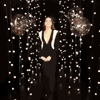 a woman is standing in front of balloons and lights