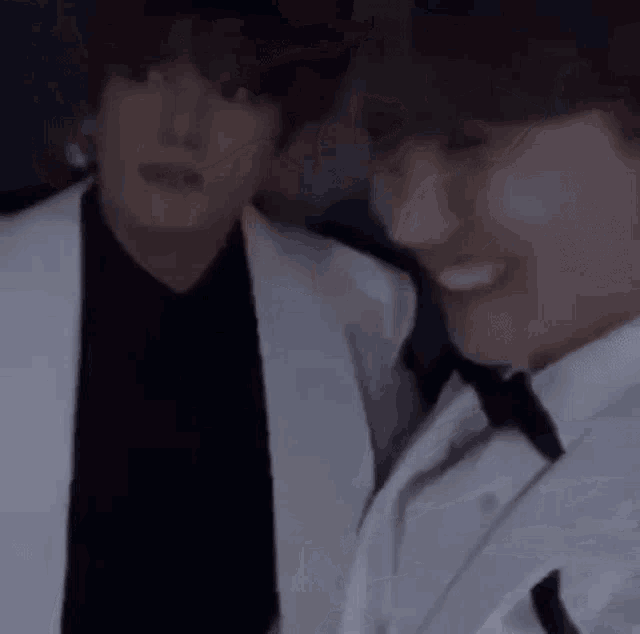 two men are standing next to each other and smiling .
