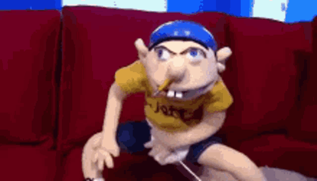 a stuffed animal is sitting on a red couch smoking a cigarette .