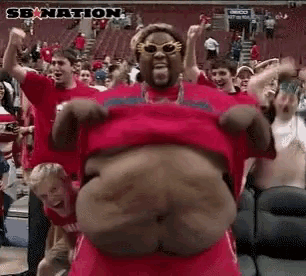 a man in a red shirt is dancing in front of a crowd with sb nation written in the corner