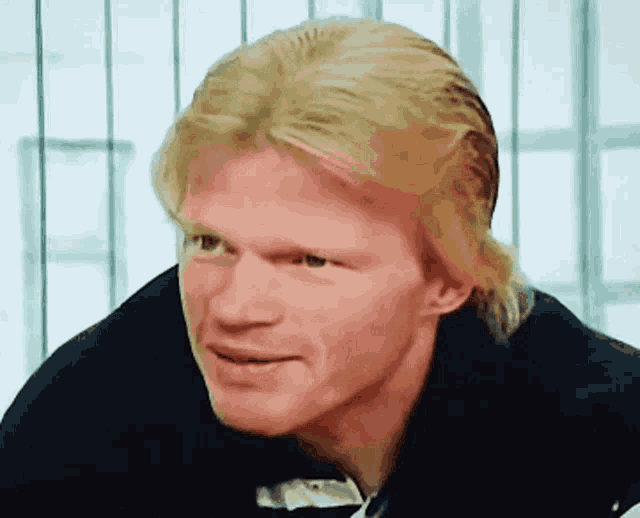 a man with blonde hair and a ponytail is smiling