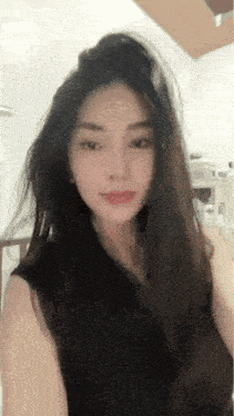 a woman with long hair is wearing a black tank top and making a funny face .