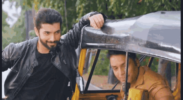two men are standing next to a yellow rickshaw .