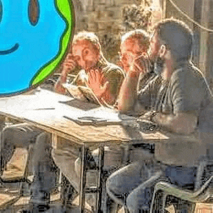 a group of men are sitting at a table with a smiley face on the wall .