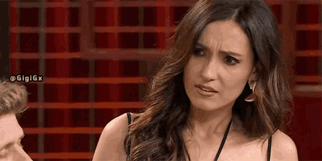a woman is making a funny face while sitting next to a man on a red background .