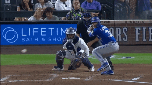 a baseball game is being played in front of an ad for lifetime bath and shower